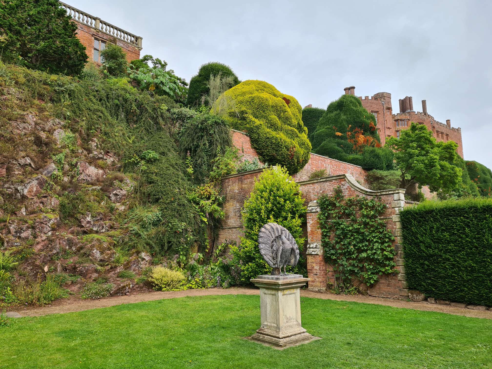 A peacock statue in Powis Castle garden with the castle showing in the rear of the picture