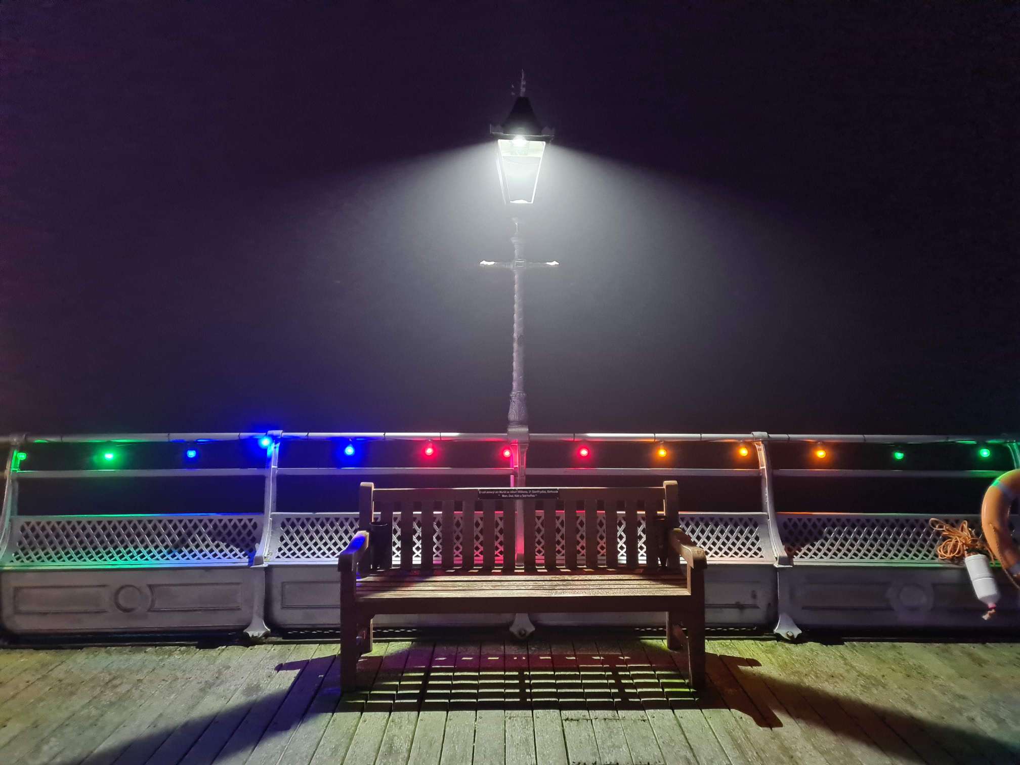 A remembrance bench lit up on Bangor Pier